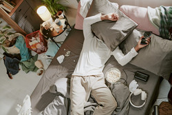 Rendetlen és koszos szobában egy férfi fekszik az ágyon